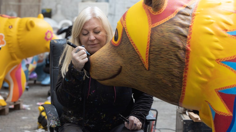 Close up of a female artist adding details to the face of a bright yellow bear